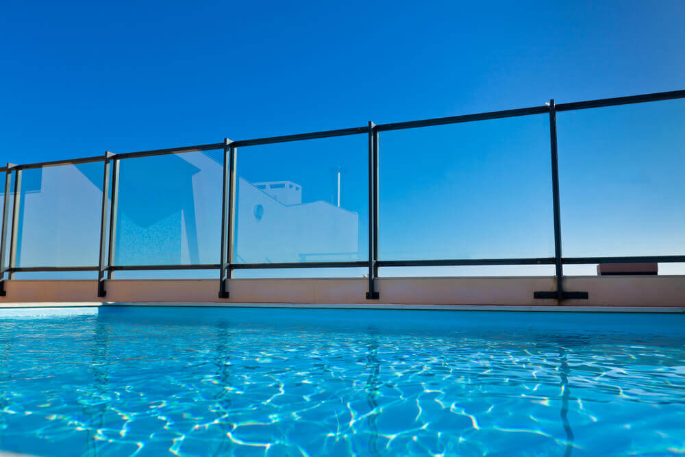 low angle shot from inside a pool looking up at a glass fence with a rich blue sky by pool fencing Toowoomba